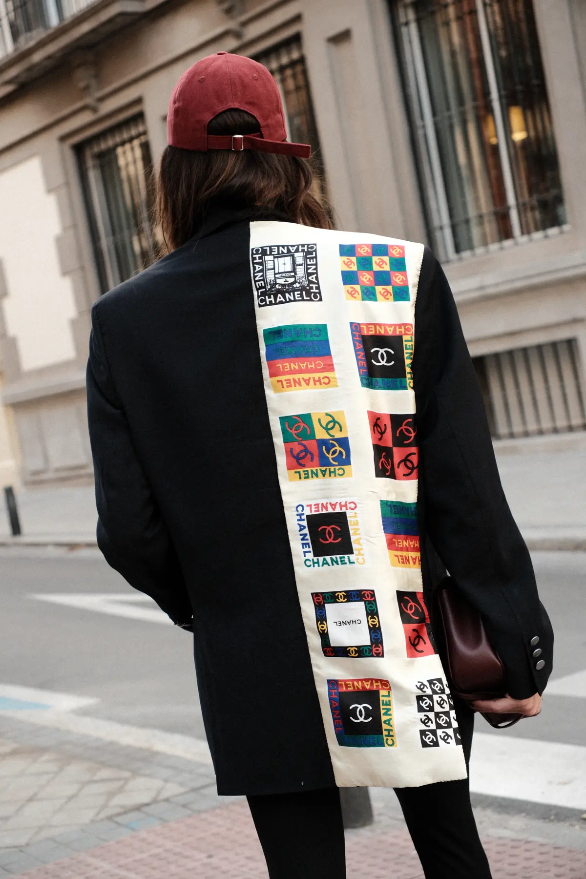 Parché Studio jeans with the red embroidered logo, worn seated on a Madrid kerb